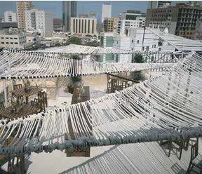 Rope tensile shade structure installed above a public walkway